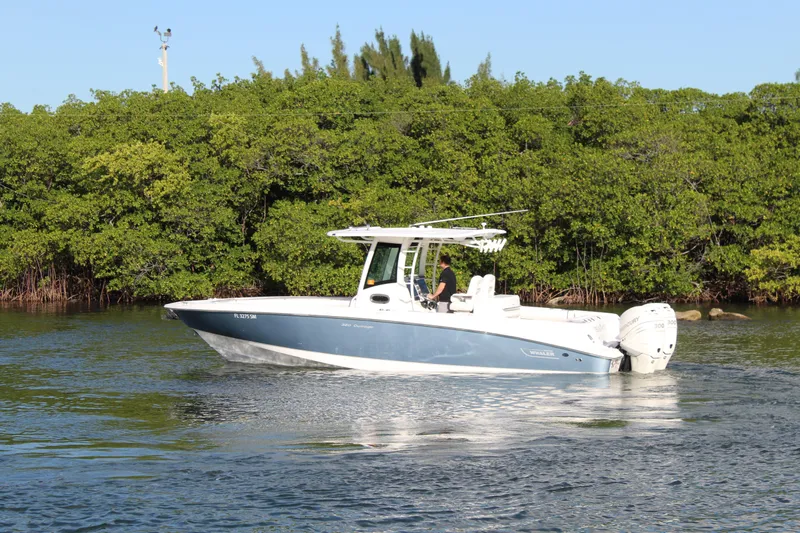 Better Than Most Yacht Photos Pics 2015 Boston Whaler 320 Outrage boat cruising near lush green shoreline.