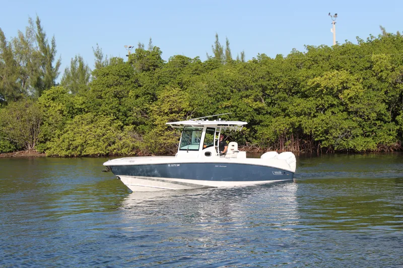 Better Than Most Yacht Photos Pics 2015 Boston Whaler 320 Outrage boat cruising on calm water near lush greenery.