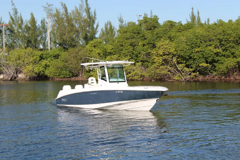 Better Than Most Yacht Photos Pics 2015 Boston Whaler 320 Outrage boat on calm water near lush greenery.