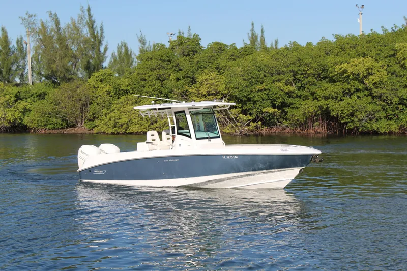 Better Than Most Yacht Photos Pics 2015 Boston Whaler 320 Outrage boat cruising on calm water near lush greenery.