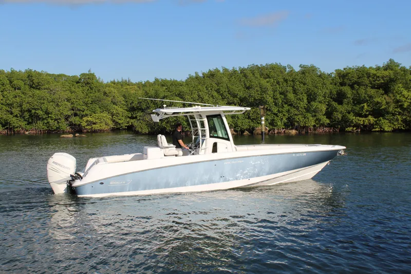 Better Than Most Yacht Photos Pics 2015 Boston Whaler 320 Outrage boat cruising on calm water near lush greenery.