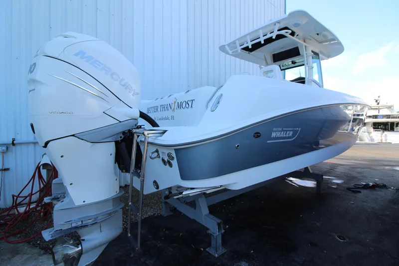 Better Than Most Yacht Photos Pics 2015 Boston Whaler 320 Outrage boat with dual Mercury engines, docked near a building.