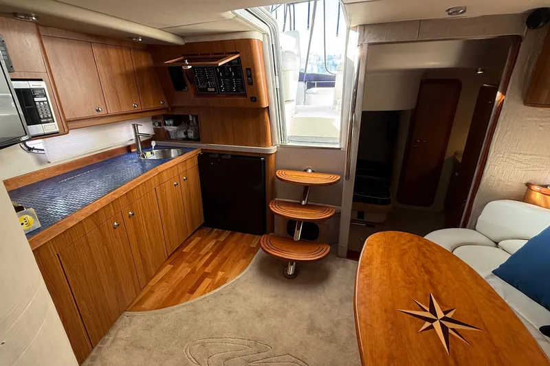  Yacht Photos Pics 2003 Regal Commodore 4260 yacht interior with wooden cabinetry, kitchenette, and cozy seating area.