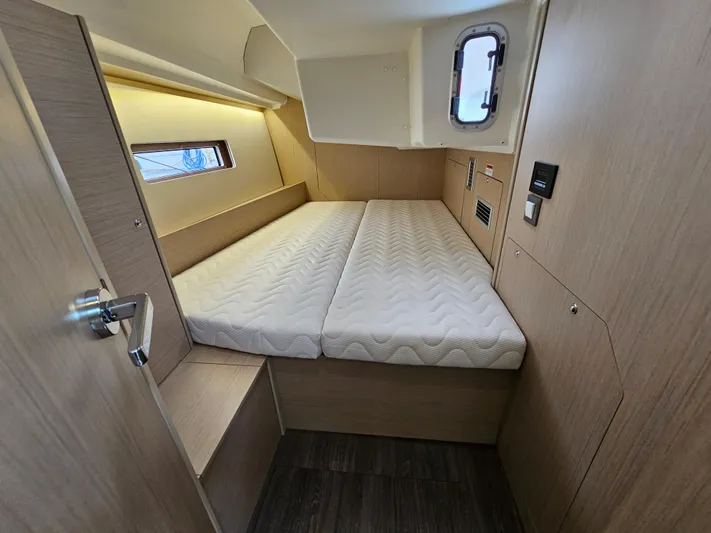  Yacht Photos Pics 2024 Beneteau Oceanis 40.1 cabin interior with bed, wooden finish, and porthole window.