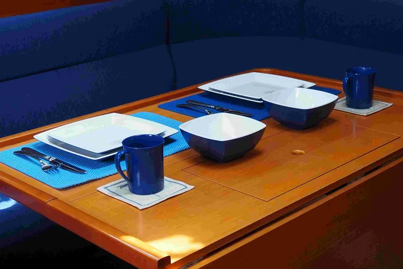 Falcon Yacht Photos Pics Elegant dining setup on a 2004 Dufour 40 Performance yacht, featuring blue and white tableware.