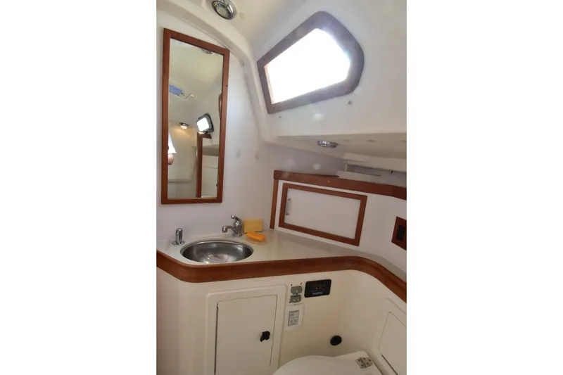 Zia Yacht Photos Pics 2004 Sabre 386 yacht bathroom with sink, mirror, and wooden accents.