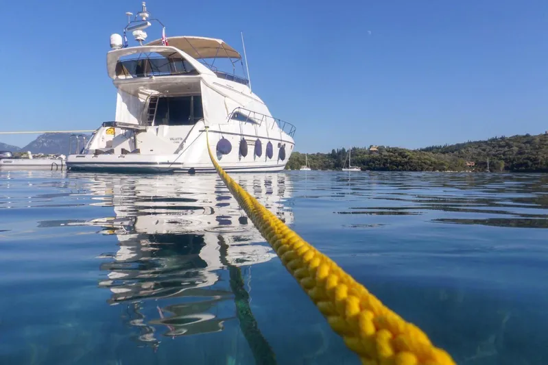  Yacht Photos Pics Luxury yacht Princess 56 (2001) anchored on calm water with a yellow mooring line.
