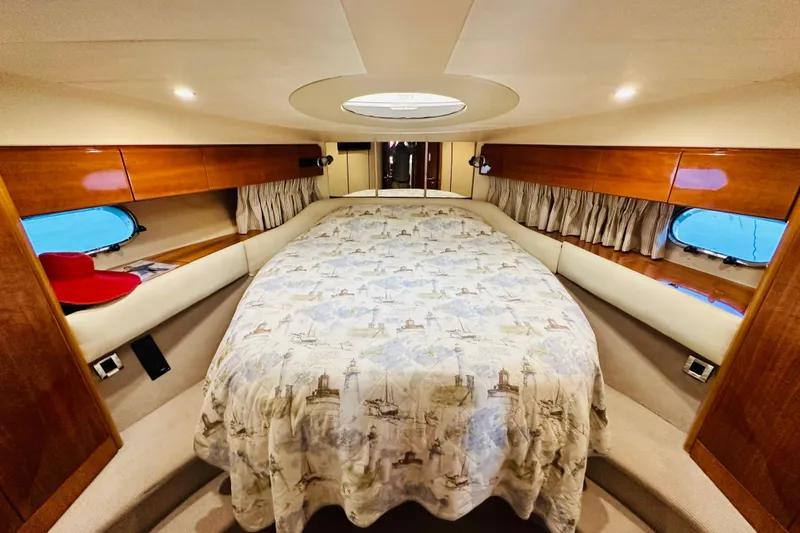  Yacht Photos Pics Luxurious cabin interior of 2001 Princess 56 yacht with cozy bed and wooden accents.