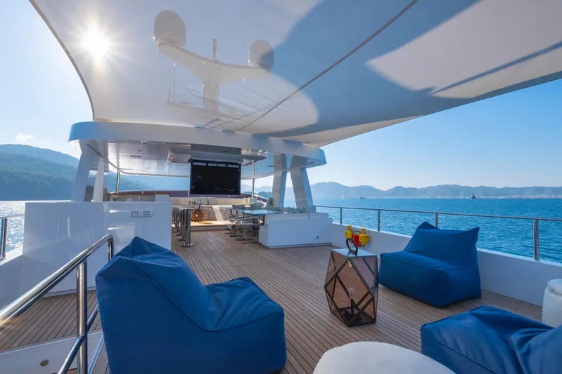  Yacht Photos Pics Luxurious 2022 Custom 85 Semi Displacement Trawler yacht deck with blue seating and ocean view.