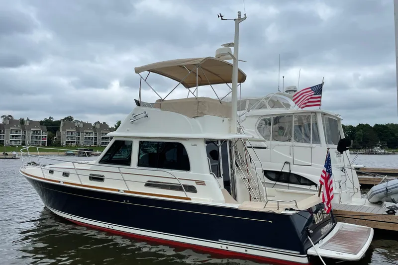 Bad Dog Yacht Photos Pics 2021 Sabre 42 Fly Bridge yacht docked, featuring American flags and a scenic waterfront backdrop.