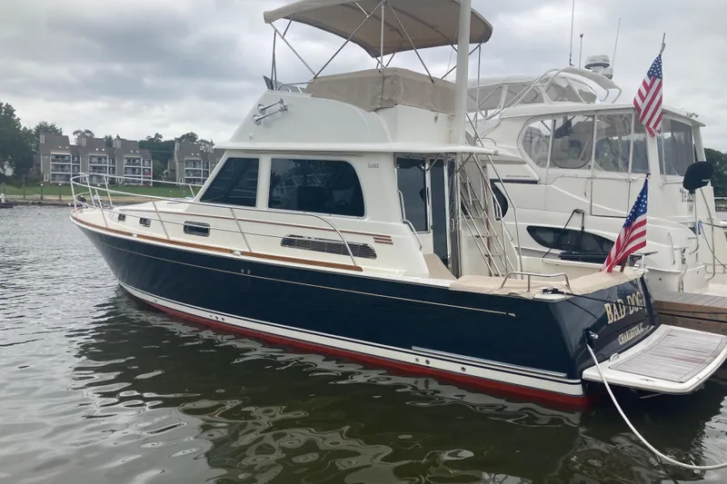Bad Dog Yacht Photos Pics 2021 Sabre 42 Fly Bridge yacht docked, featuring sleek design and American flag.