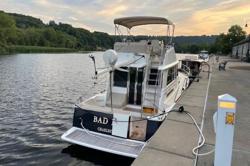 Bad Dog Yacht Photos Pics 2021 Sabre 42 Fly Bridge yacht docked by a scenic riverside at sunset.