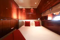 Luxurious cabin interior of 1997 Arno Leopard 27m yacht with wood paneling and red accents.