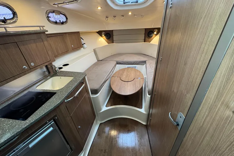 Hammer Down Yacht Photos Pics 2016 Boston Whaler 315 Conquest cabin interior with kitchenette and seating area.