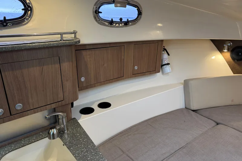 Hammer Down Yacht Photos Pics Interior of 2016 Boston Whaler 315 Conquest, featuring wood cabinets and cozy seating area.