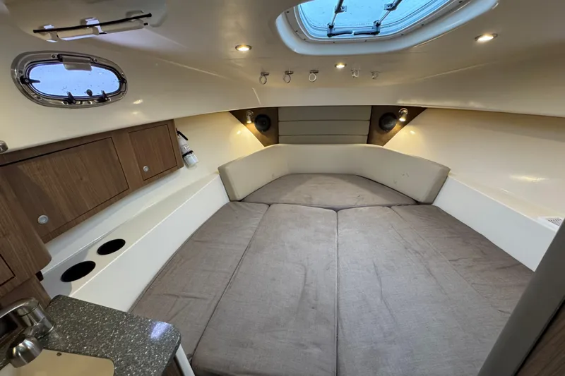 Hammer Down Yacht Photos Pics 2016 Boston Whaler 315 Conquest cabin interior with cozy bed and wooden cabinets.
