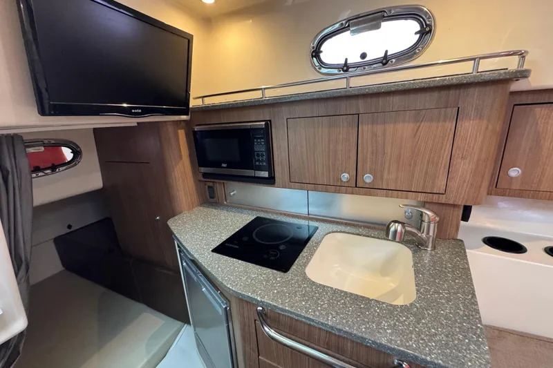 Hammer Down Yacht Photos Pics 2016 Boston Whaler 315 Conquest interior kitchen with TV, microwave, sink, and stove.