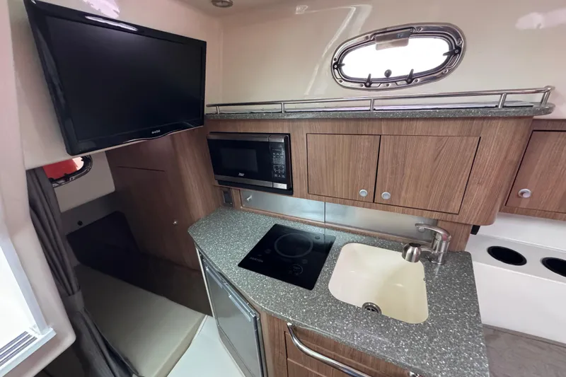 Hammer Down Yacht Photos Pics 2016 Boston Whaler 315 Conquest interior kitchen with TV, microwave, sink, and stove.