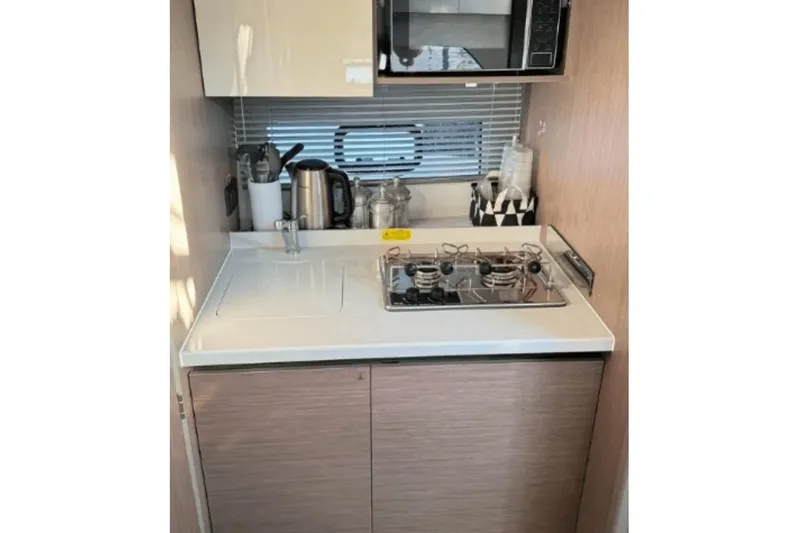  Yacht Photos Pics Compact kitchen in 2022 Beneteau Gran Turismo 36 yacht with stove, kettle, and microwave.