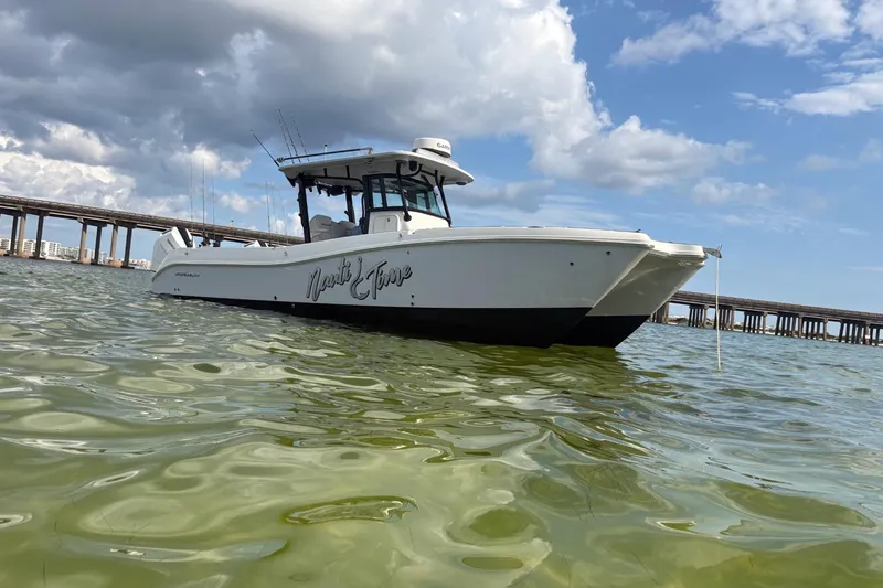 Nauti Time Yacht Photos Pics 2024 World Cat 325 CC boat on water with bridge and cloudy sky background.