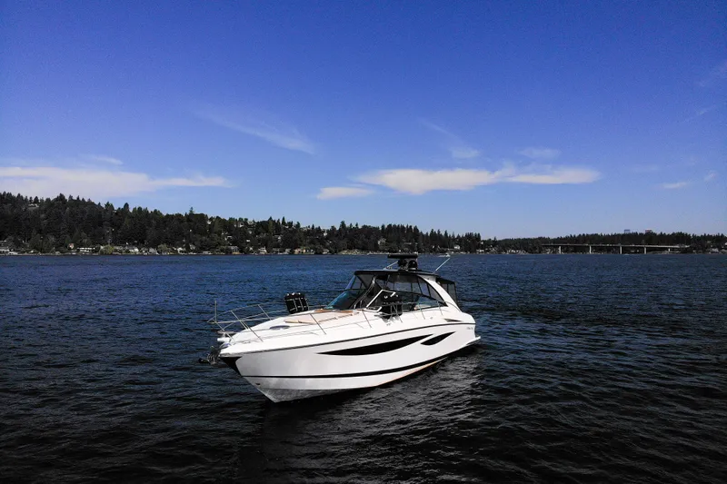  Yacht Photos Pics 2018 Cobalt 46 Yacht on serene lake with forested shoreline and clear blue sky.