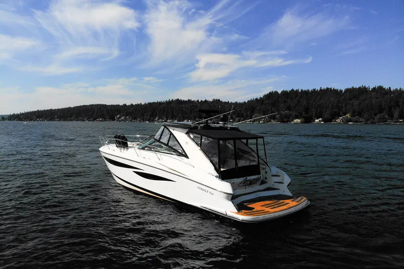  Yacht Photos Pics 2018 Cobalt 46 Yacht on serene lake with forested shoreline and blue sky.