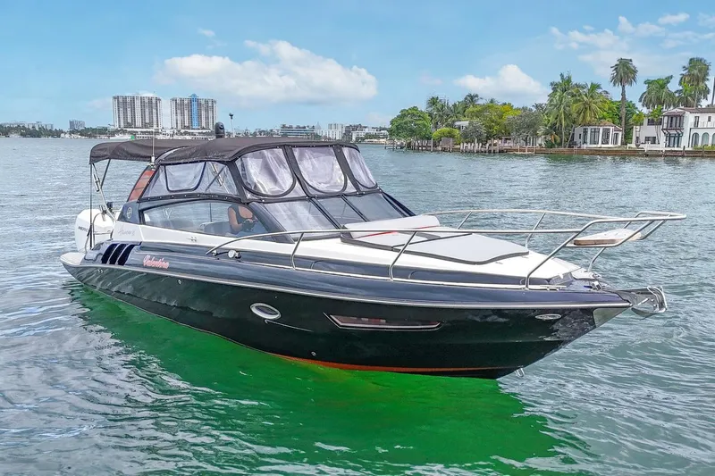  Yacht Photos Pics 2024 Hanover 305 boat cruising on a scenic waterway with city skyline backdrop.