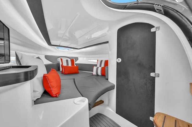  Yacht Photos Pics 2024 Hanover 305 boat interior with modern design, featuring gray seating and red-striped cushions.
