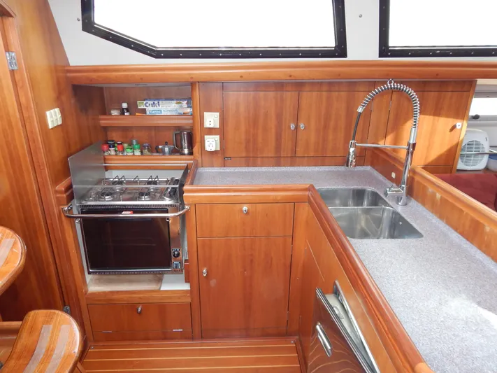  Yacht Photos Pics Wooden yacht kitchen with stove, sink, and storage in 1999 Oyster 42 Aft Cockpit Deck Saloon.
