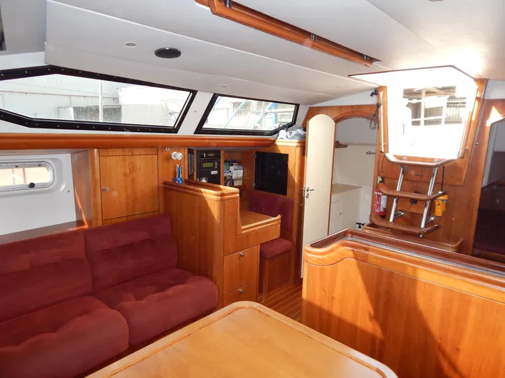  Yacht Photos Pics Interior of 1999 Oyster 42 Aft Cockpit Deck Saloon with wood finish and red seating.