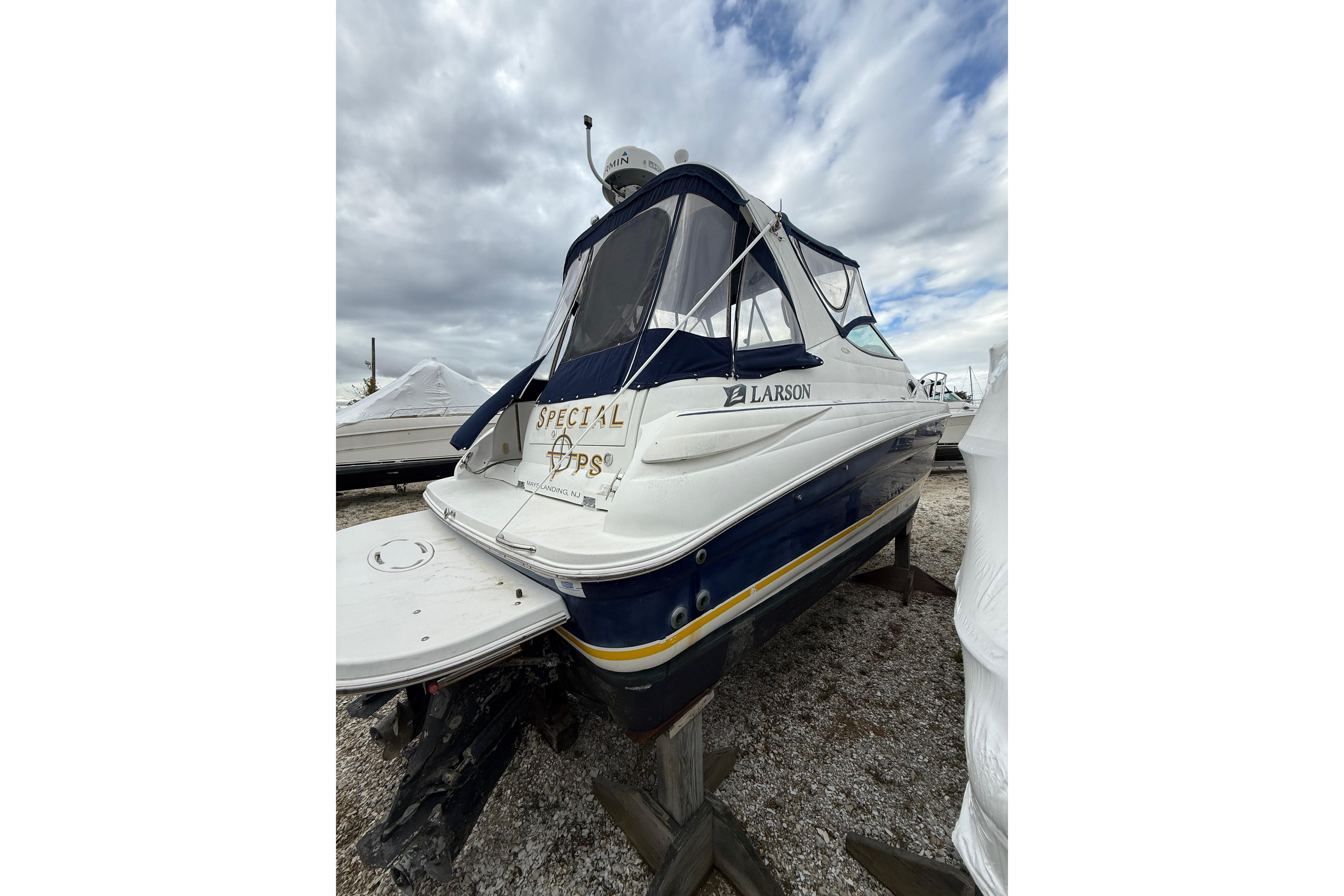 2005 Larson Cabrio 290 boat on dry dock under cloudy skies.