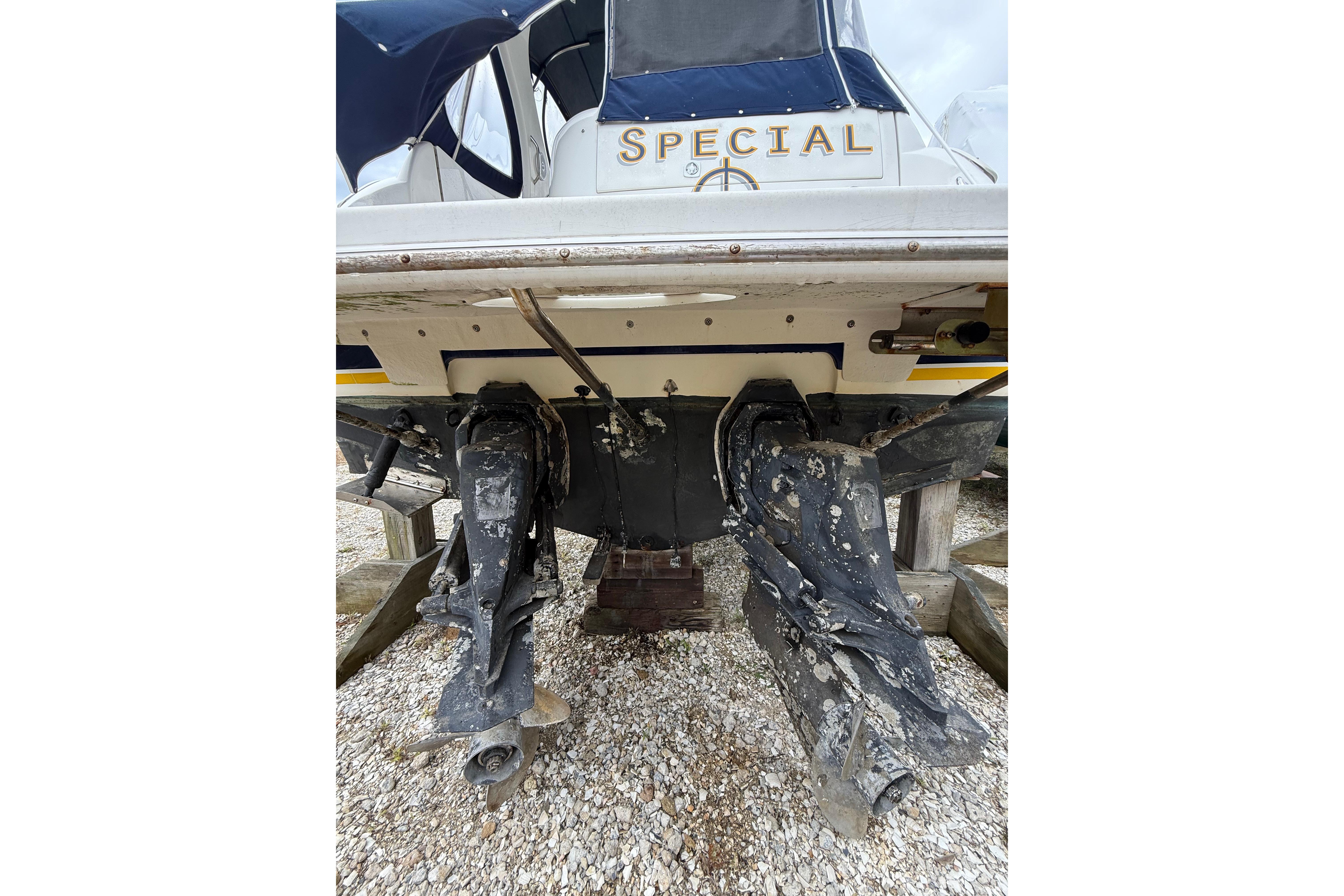 2005 Larson Cabrio 290 boat stern with dual outboard motors on gravel.