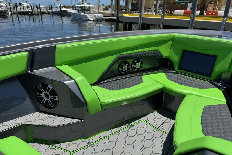  Yacht Photos Pics 2023 Adrenaline 47 boat interior with green seating, speakers, and a waterfront view.
