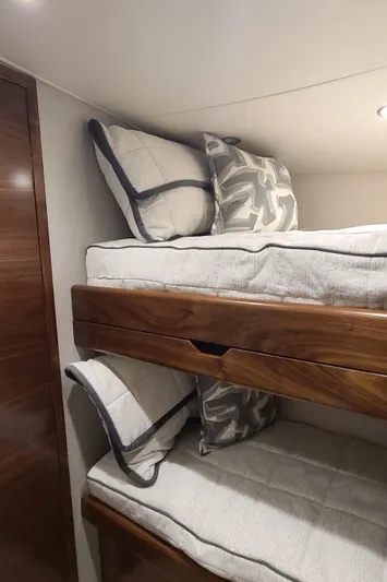 Nomad Yacht Photos Pics 2024 Viking 54 Convertible yacht interior with wooden bunk beds and plush pillows.
