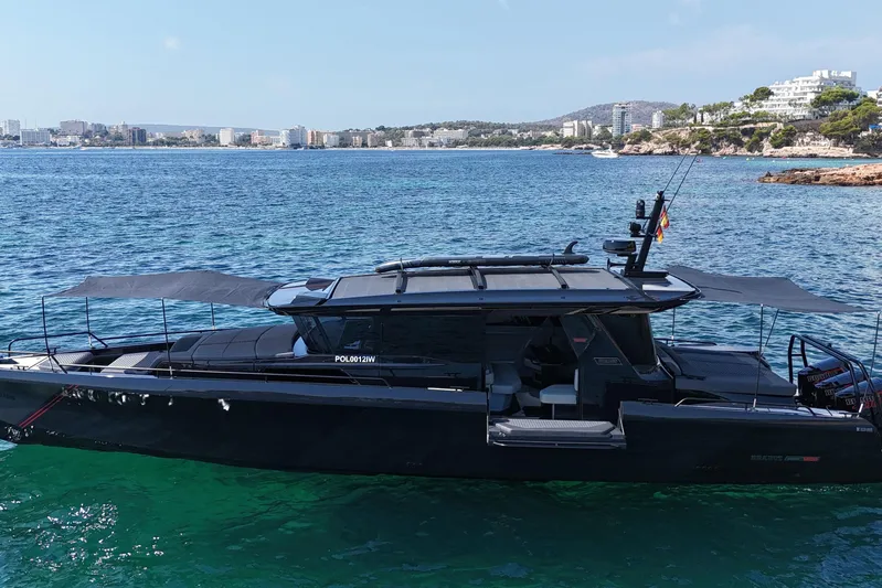 Ex Felgenhauer Yacht Photos Pics 2023 BRABUS Shadow 1200 Cross Cabin yacht on clear blue water, coastal cityscape in background.