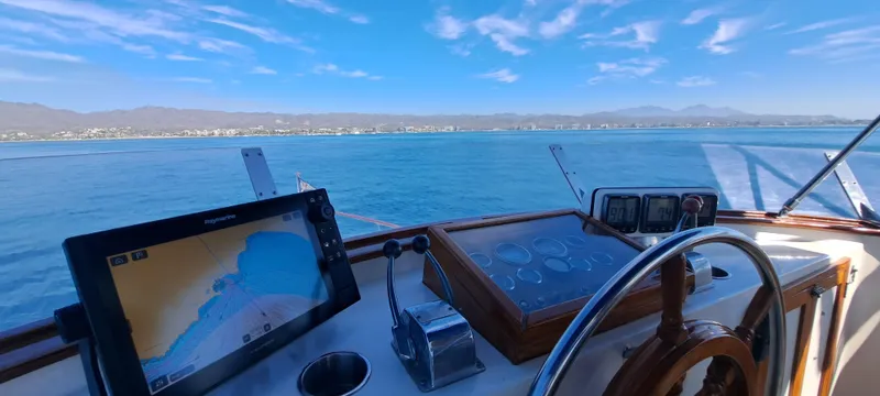 Ballena Blanca Yacht Photos Pics 1985 DeFever 44 Trawler helm with navigation equipment, overlooking calm blue waters.