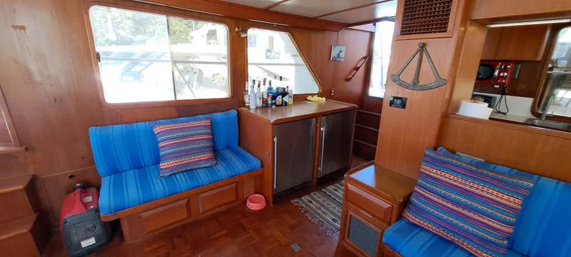 Ballena Blanca Yacht Photos Pics Interior of 1985 DeFever 44 Trawler with blue seating and wooden cabinetry.