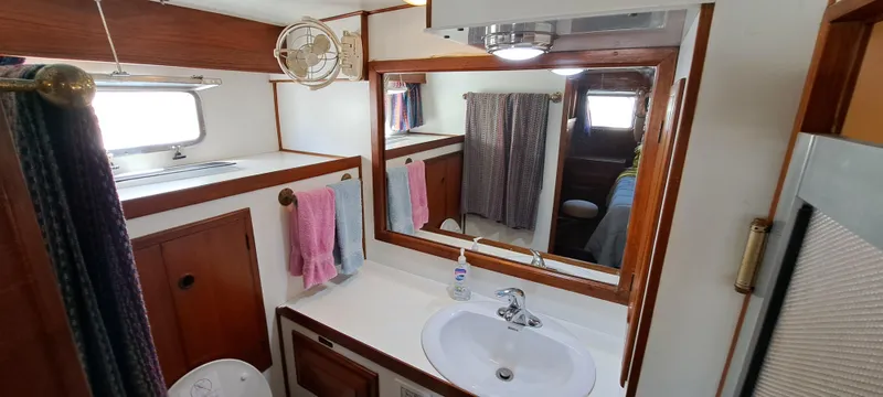 Ballena Blanca Yacht Photos Pics 1985 DeFever 44 Trawler bathroom with wooden cabinetry, sink, and mirror.