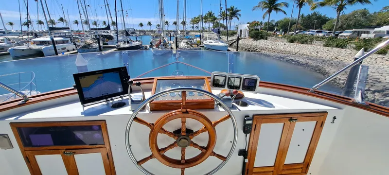 Ballena Blanca Yacht Photos Pics 1985 DeFever 44 Trawler helm with wooden wheel, marina view, and navigation equipment.