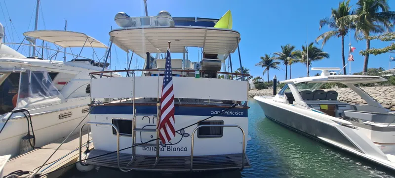 Ballena Blanca Yacht Photos Pics 1985 DeFever 44 Trawler docked, displaying American flag, surrounded by palm trees and boats.