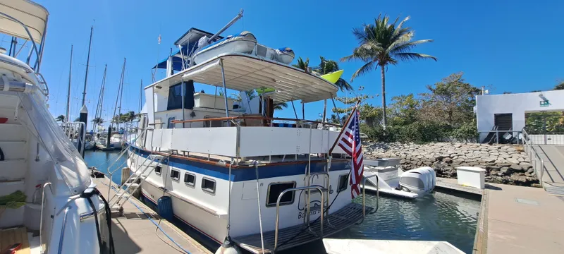 Ballena Blanca Yacht Photos Pics 1985 DeFever 44 Trawler docked at marina with American flag, clear blue sky.