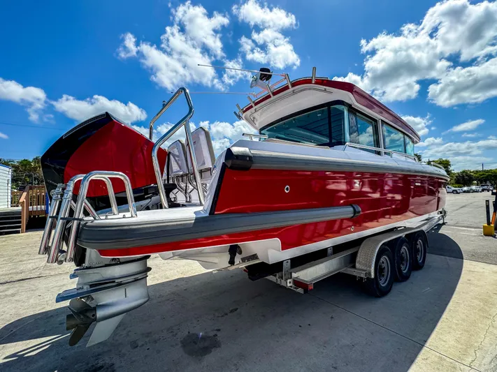  Yacht Photos Pics 2023 Axopar 37 XC CROSS CABIN boat on trailer under a bright blue sky.