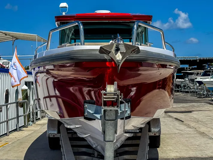 Yacht Photos Pics 2023 Axopar 37 XC CROSS CABIN boat with red hull, docked under clear blue sky.