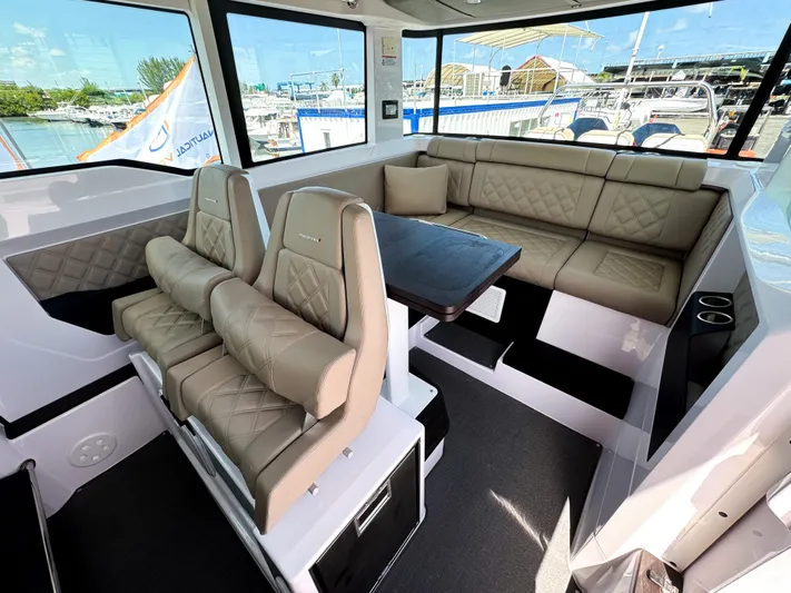  Yacht Photos Pics 2023 Axopar 37 XC CROSS CABIN interior with beige seating and table, docked at marina.