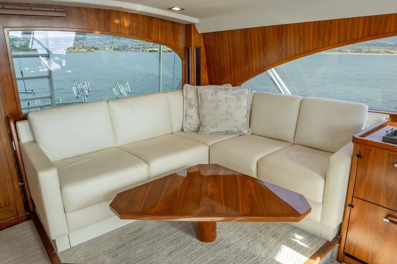 Silvertime Yacht Photos Pics Luxurious interior of 2018 Viking 80 Enclosed Bridge yacht with white leather sofa and wooden accents.