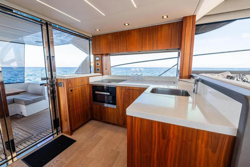  Yacht Photos Pics Luxurious Sunseeker Manhattan 52 yacht kitchen with ocean view, featuring modern wood cabinetry.