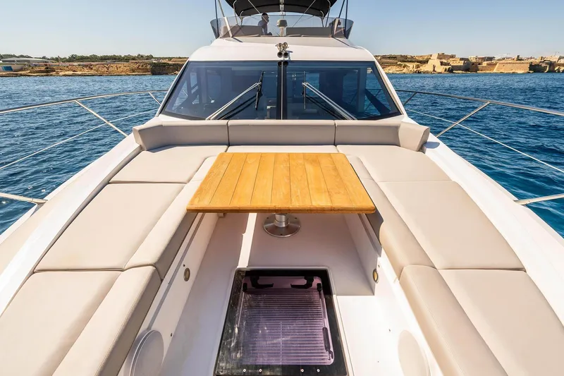  Yacht Photos Pics 2020 Sunseeker Manhattan 52 yacht deck with seating and table, cruising on blue waters.