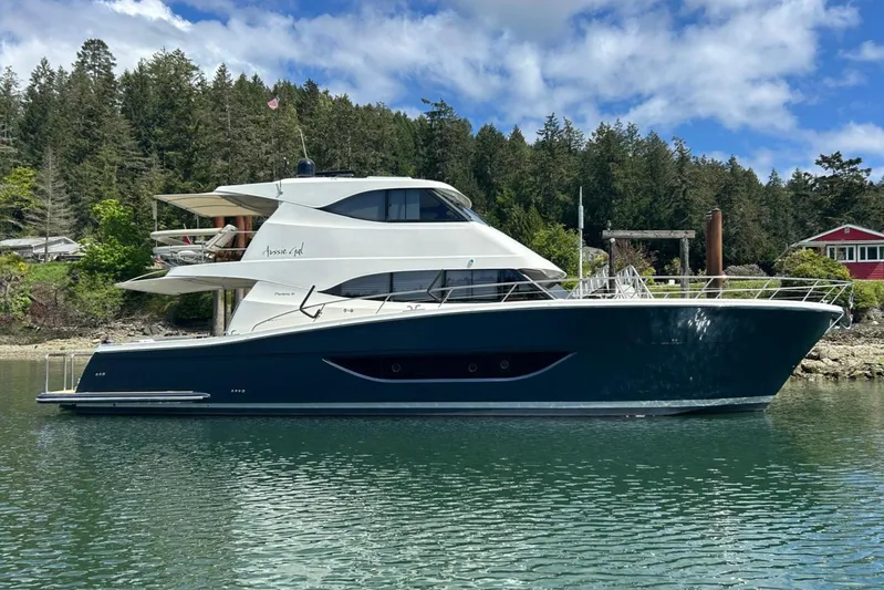  Yacht Photos Pics 2020 Maritimo M64 yacht on calm water, surrounded by lush trees and a clear sky.