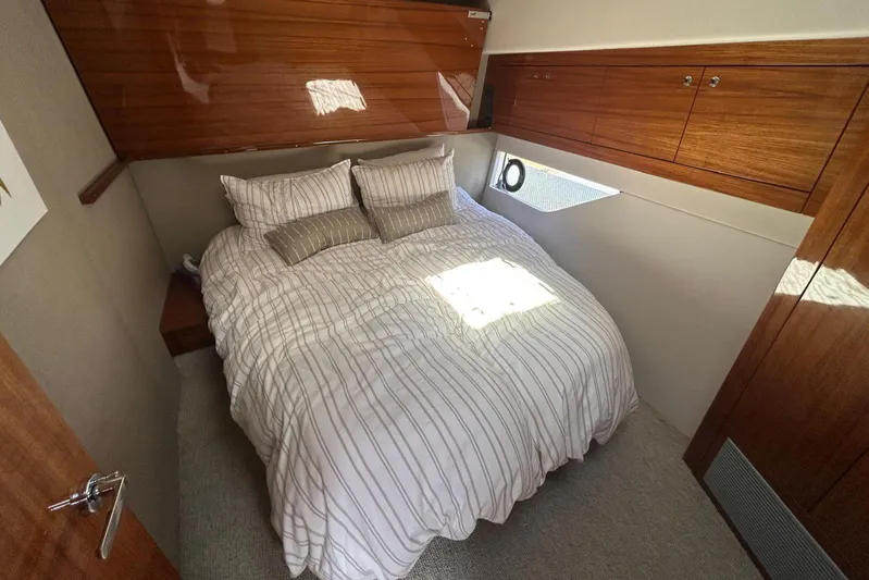  Yacht Photos Pics Luxurious bedroom interior of 2020 Maritimo M64 yacht with wood paneling and cozy bedding.