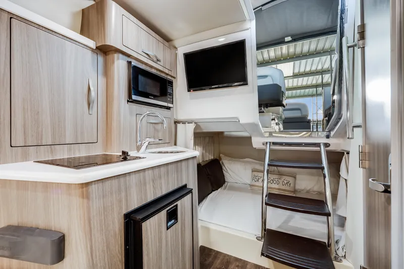 Tarini Yacht Photos Pics Interior of 2020 Regal 28 Express boat with kitchenette, bed, and TV.